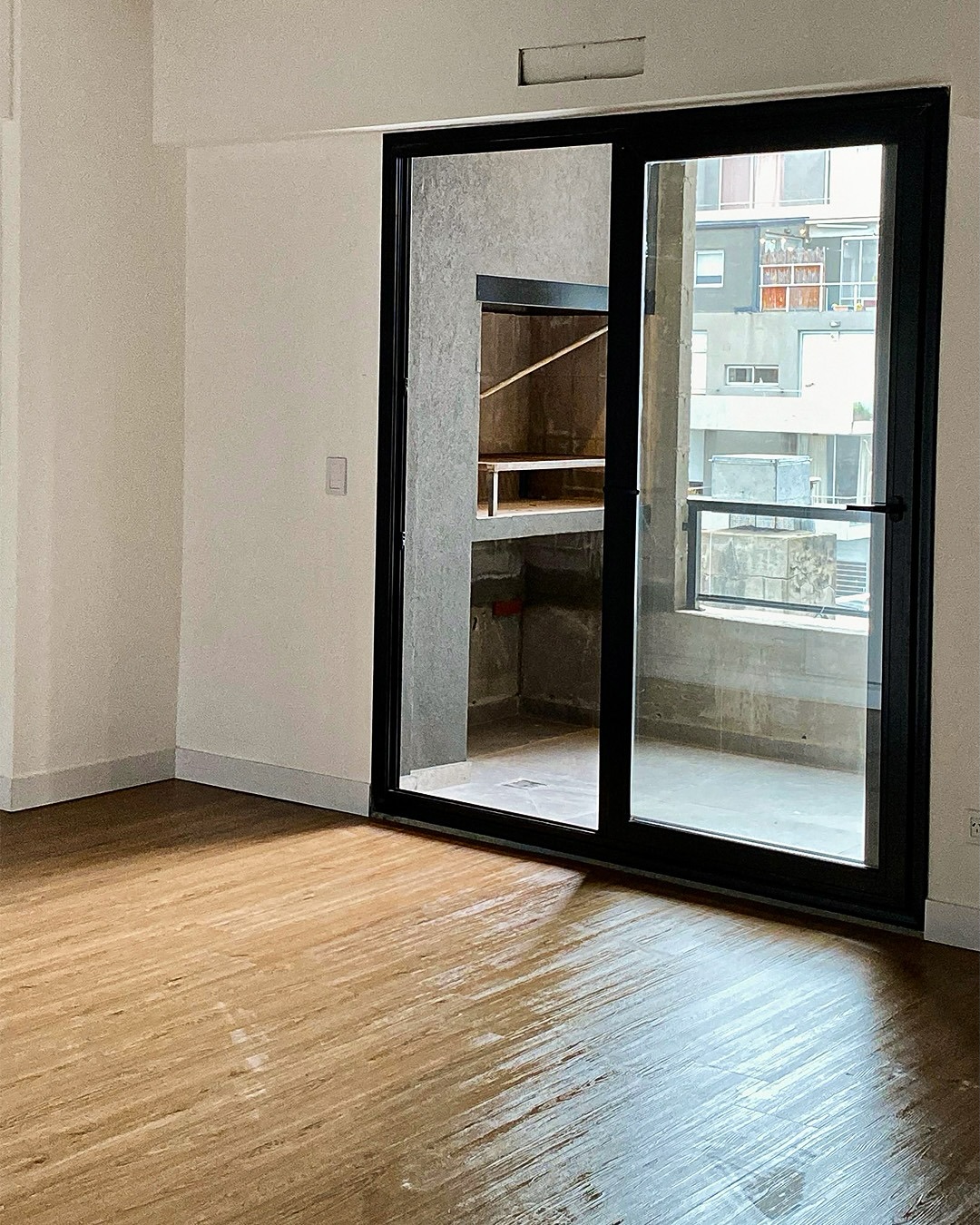 Dormitorio con piso de madera y ventanal corredizo